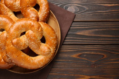 Tasty freshly baked pretzels on wooden table, top view. Space for text