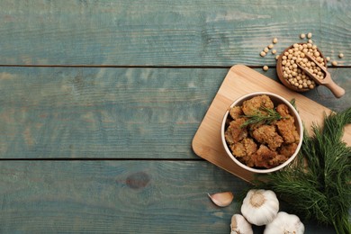 Flat lay composition with cooked soy meat and beans on light blue wooden table. Space for text