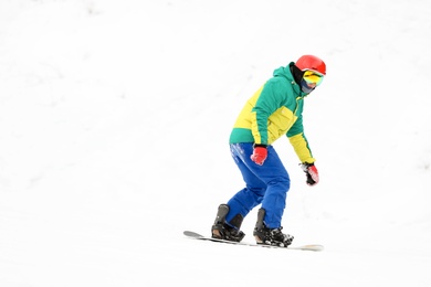 Snowboarder on slope at resort, space for text. Winter vacation