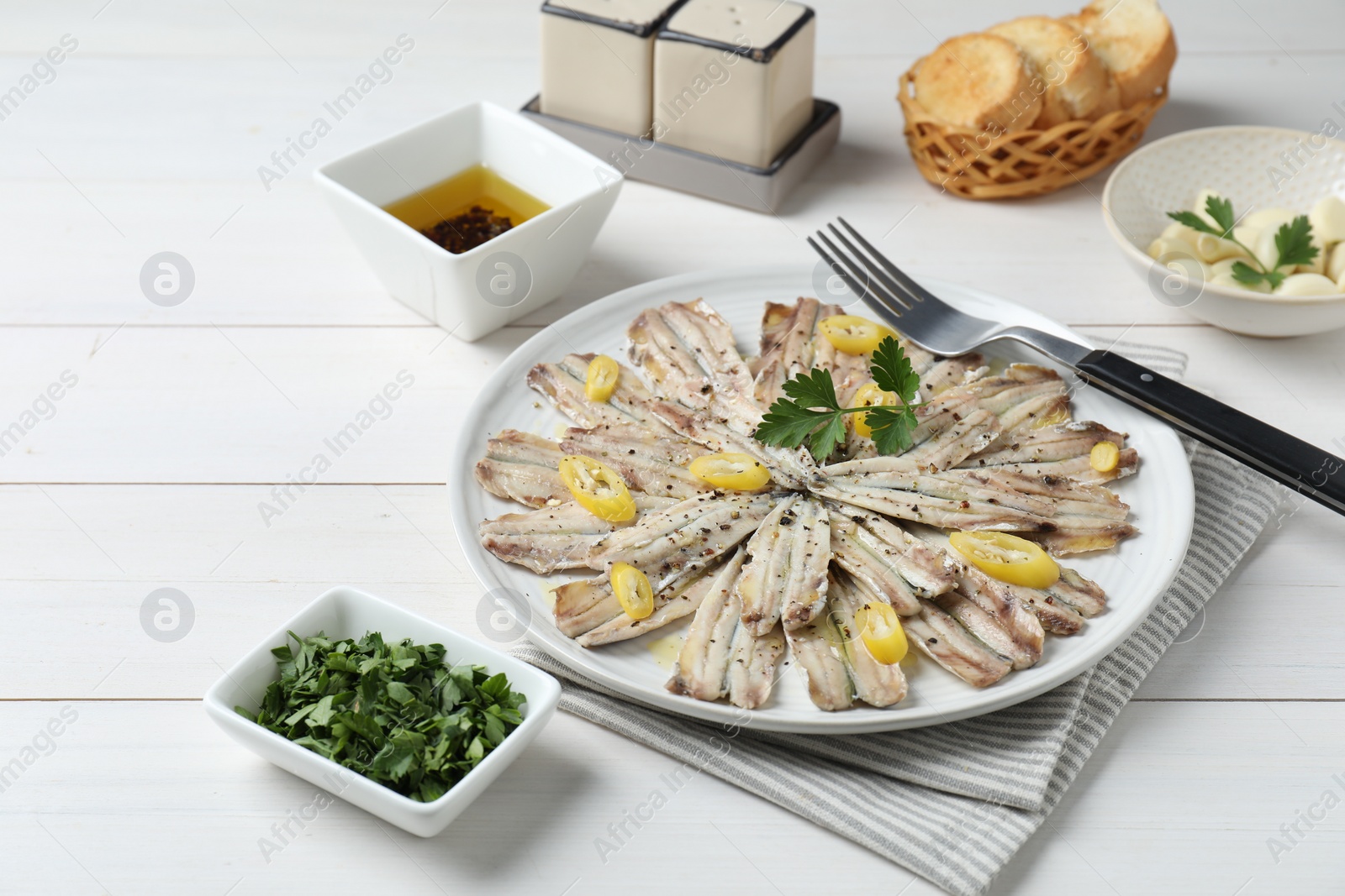 Photo of Tasty pickled anchovies served on white wooden table