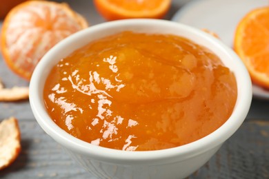 Photo of Tasty tangerine jam in bowl on table, closeup