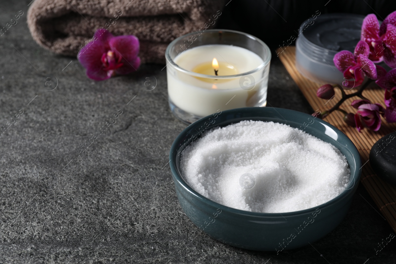 Photo of Beautiful composition with sea salt, burning candle, flowers and different spa products on grey table, space for text