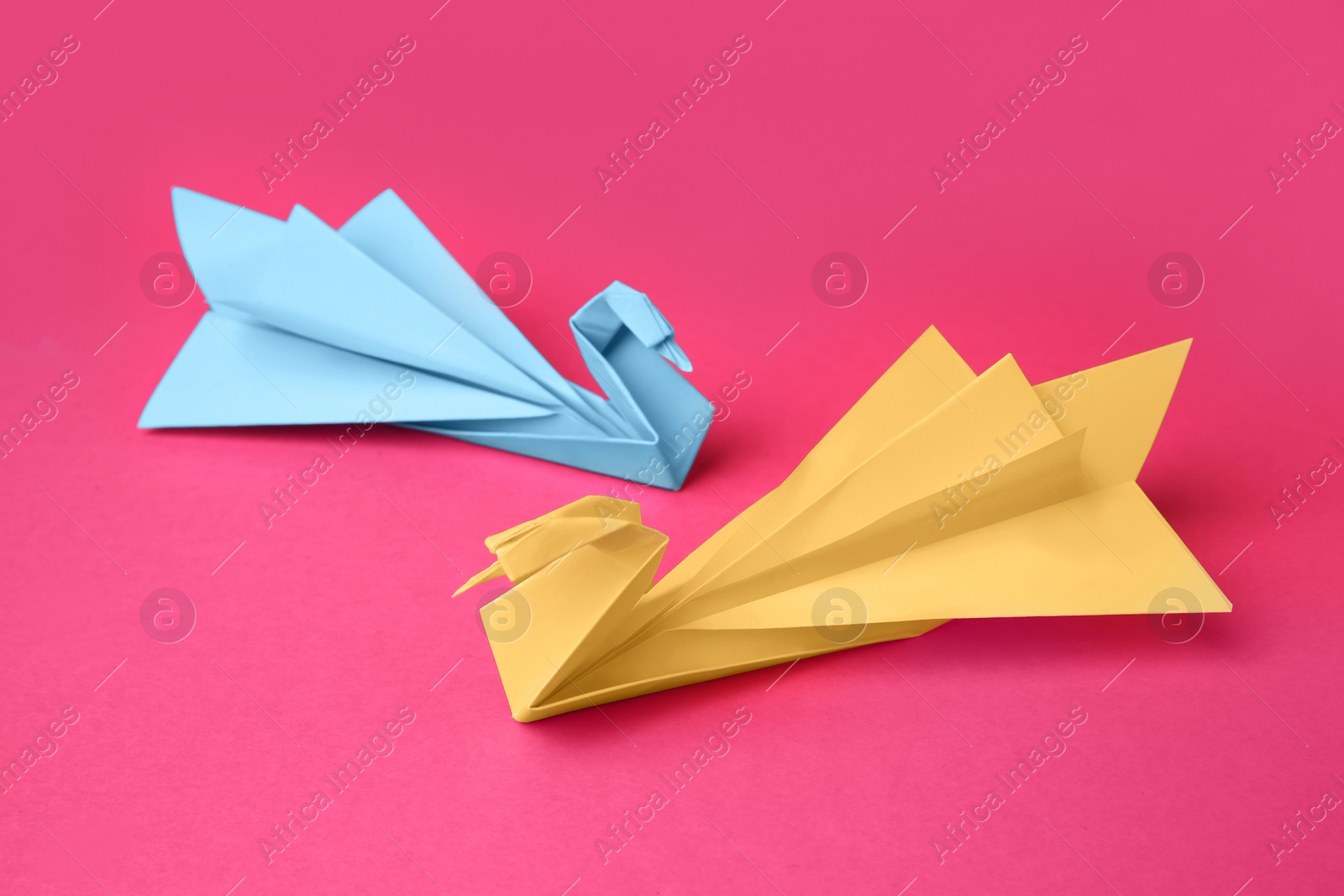 Photo of Paper swans on pink background. Origami art