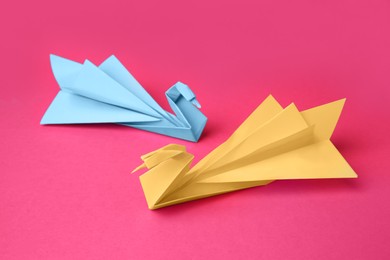 Photo of Paper swans on pink background. Origami art