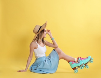 Young woman with retro roller skates on color background