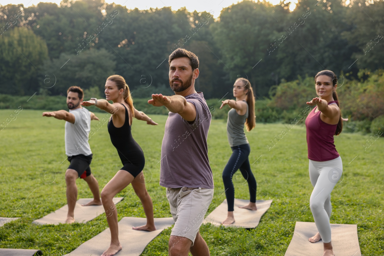 Photo of Group of people practicing yoga on mats outdoors