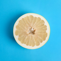 Photo of Fresh cut pomelo fruit on blue background, top view