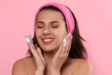 Photo of Beautiful woman applying facial cleansing foam on pink background