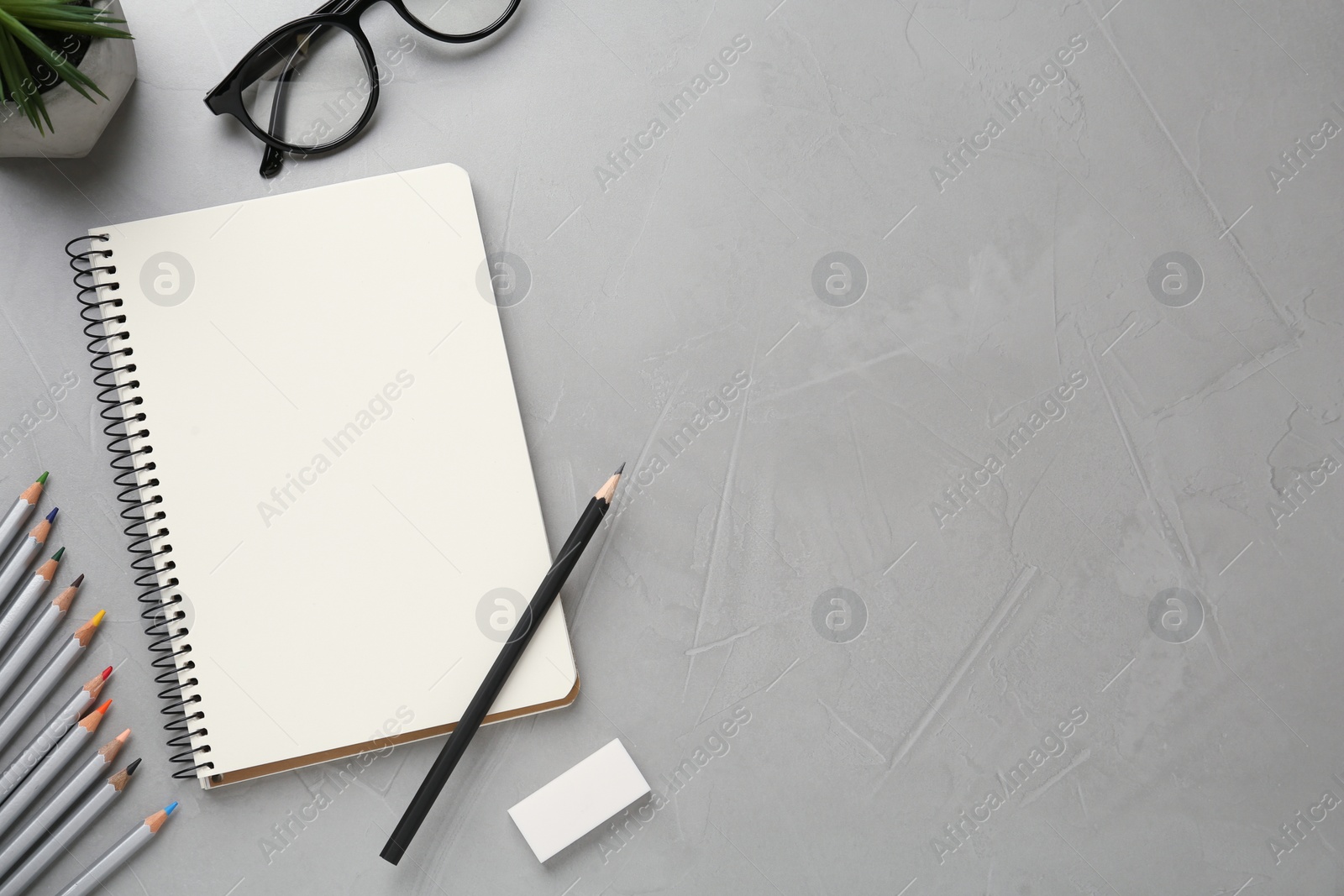 Photo of Flat lay composition with blank sketchbook on light grey stone table. Space for text