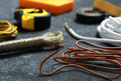Photo of Different electrical wires and tools on black textured table, closeup
