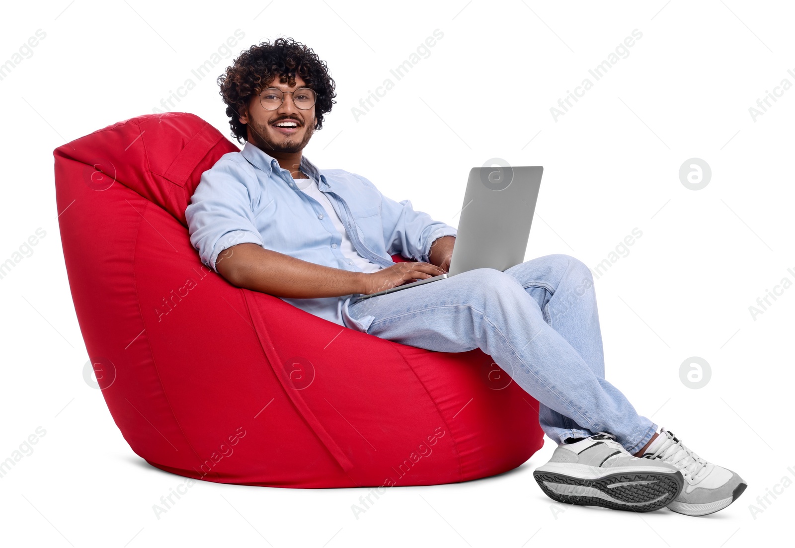 Photo of Smiling man with laptop sitting on beanbag chair against white background