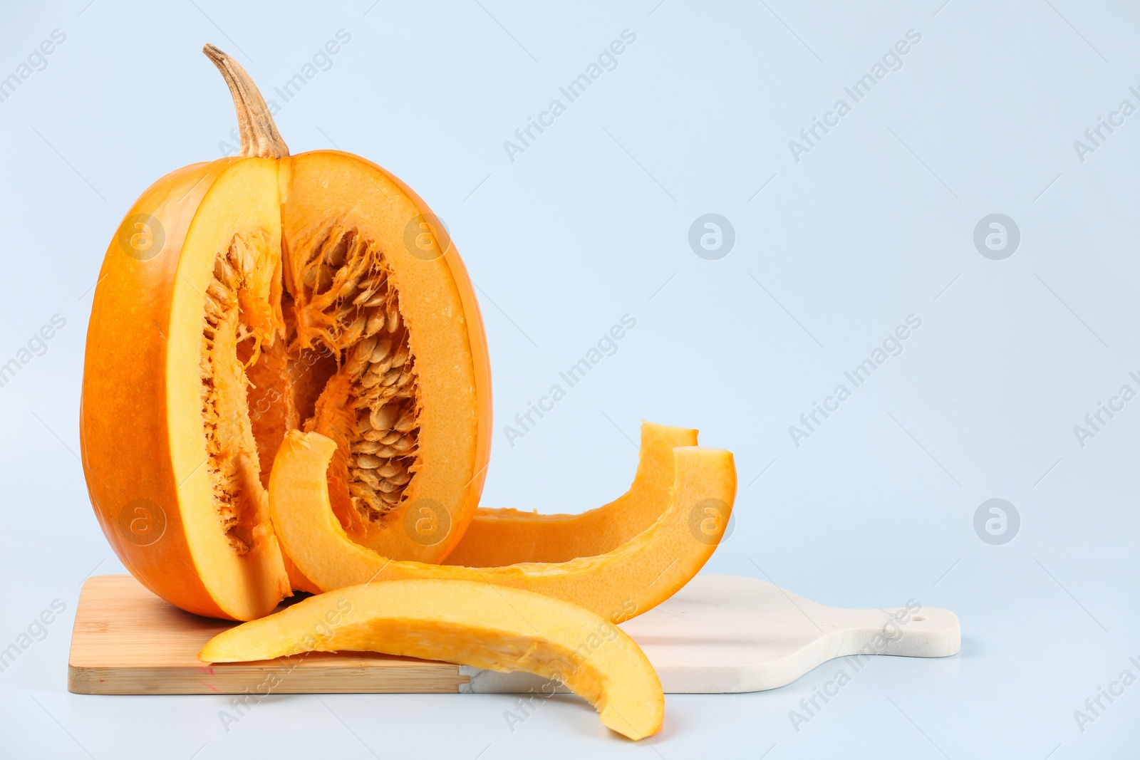 Photo of Cut fresh ripe pumpkin on light background, space for text