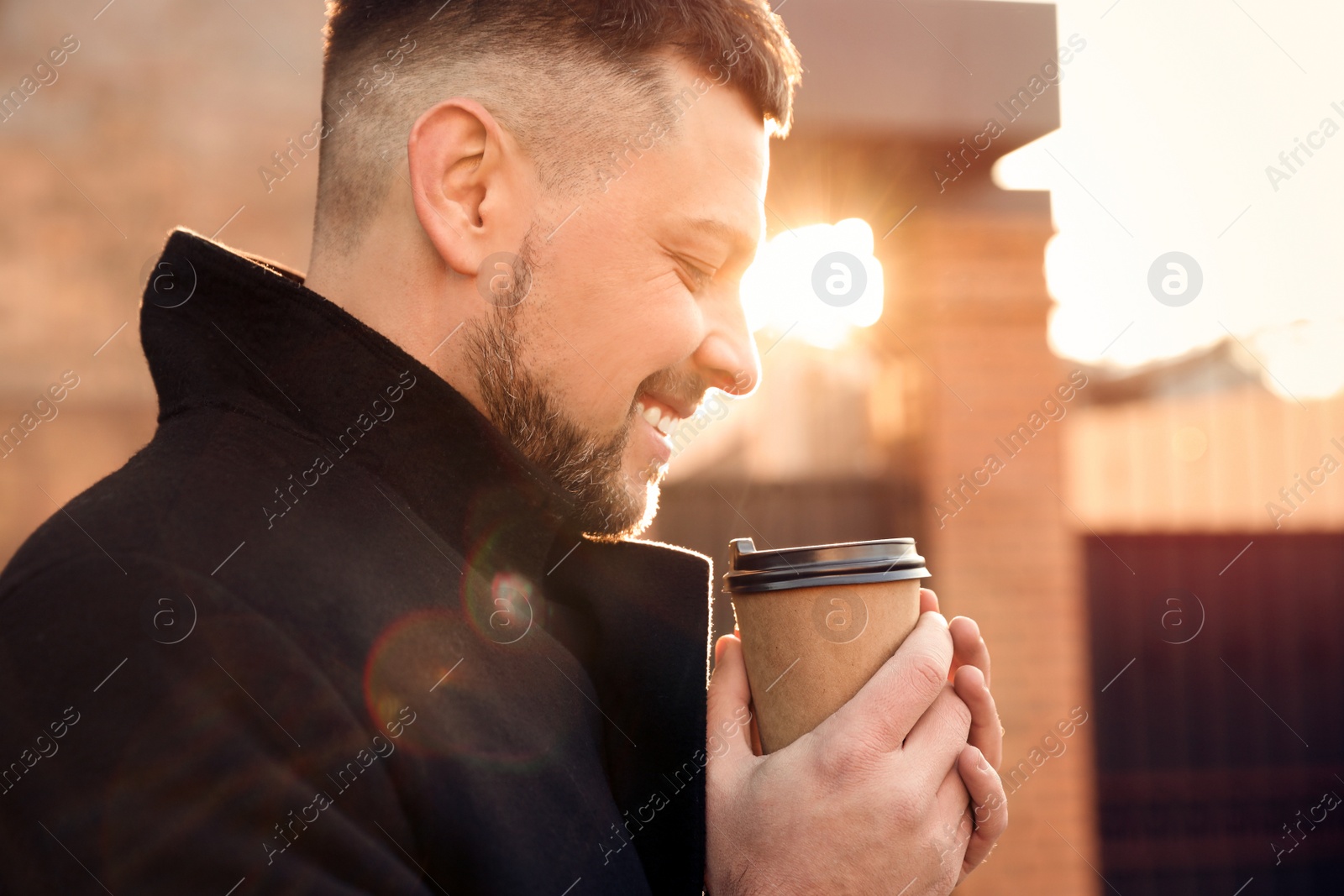 Photo of Man with cup of coffee on city street in morning