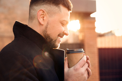 Man with cup of coffee on city street in morning