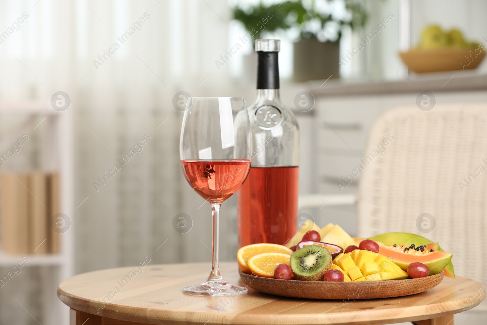 Photo of Delicious exotic fruits and wine on wooden table indoors