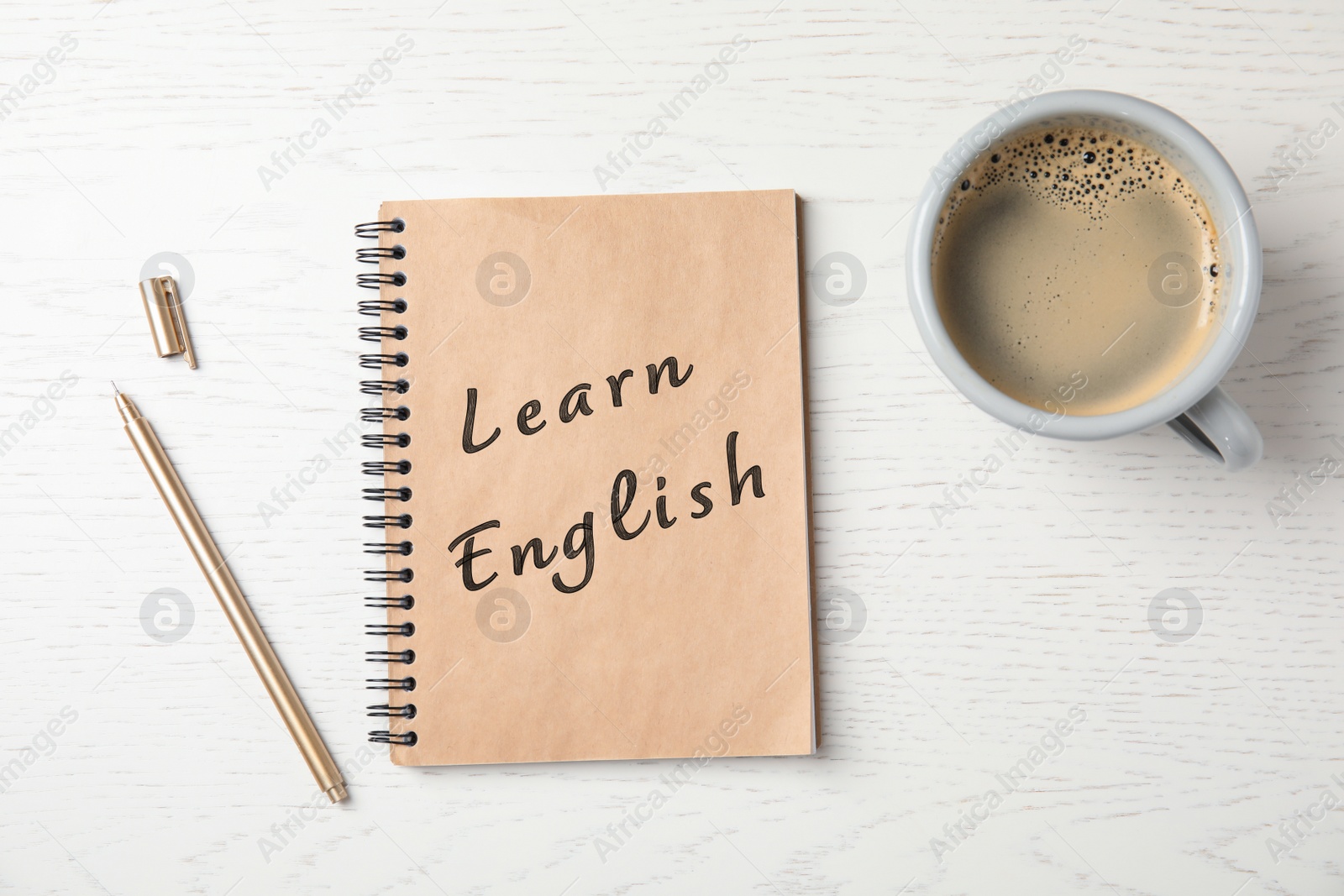 Image of Notebook with text Learn English and cup of coffee on wooden table, flat lay