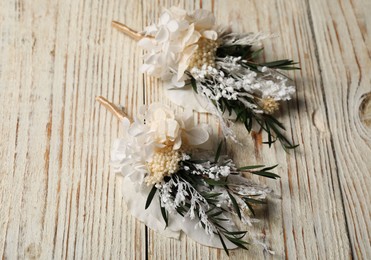 Photo of Stylish boutonnieres on light wooden table, above view