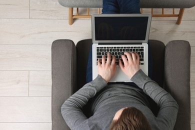 Photo of Man working with laptop in armchair, top view