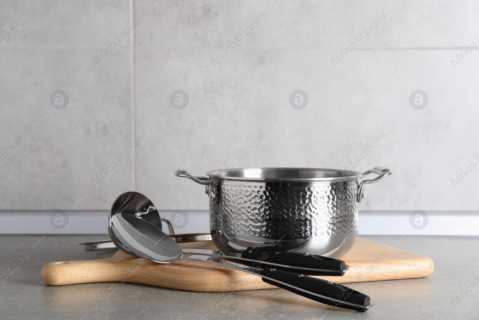 Photo of Set of different cooking utensils on grey countertop in kitchen