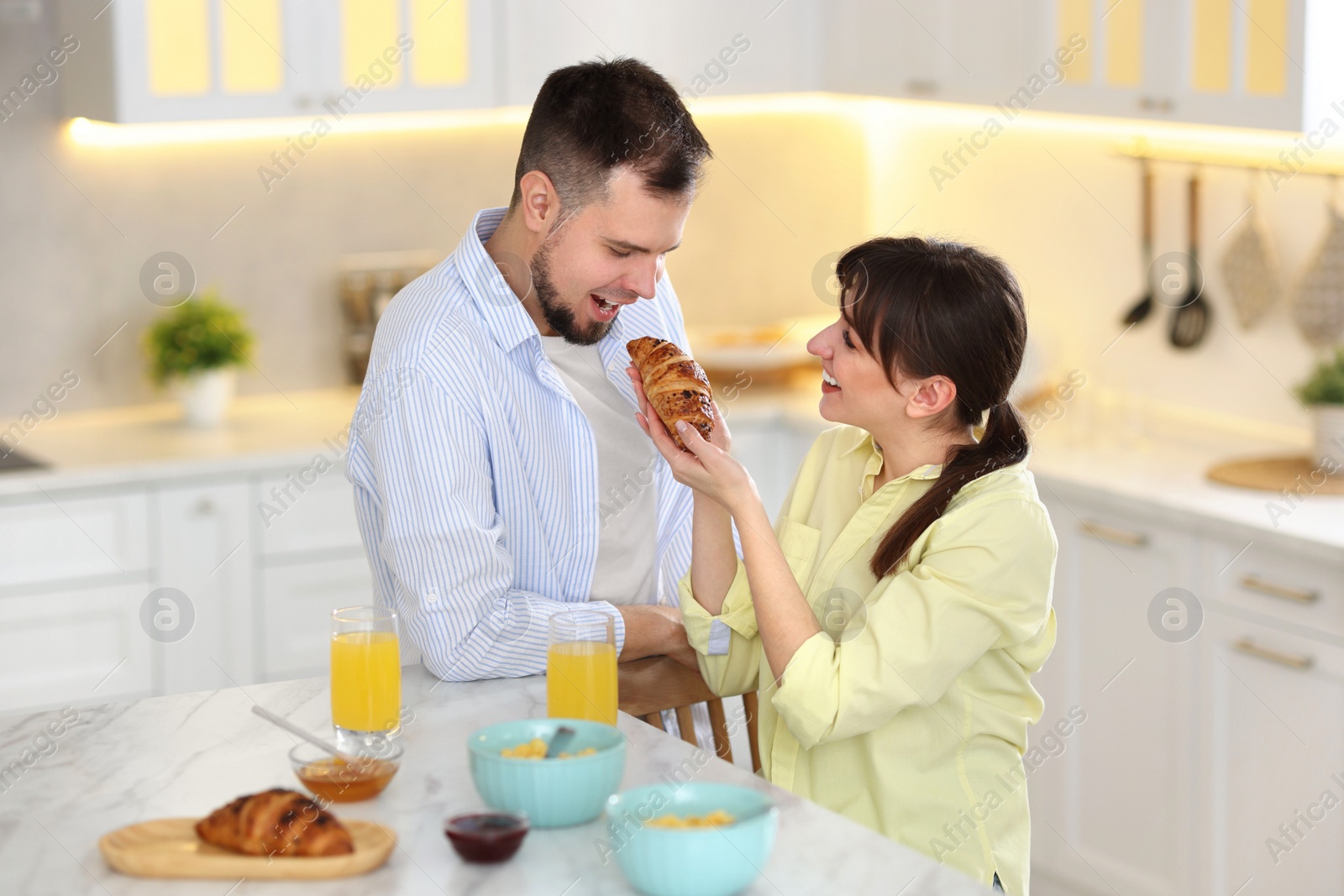 Photo of Tasty breakfast. Happy wife feeding her husband at home