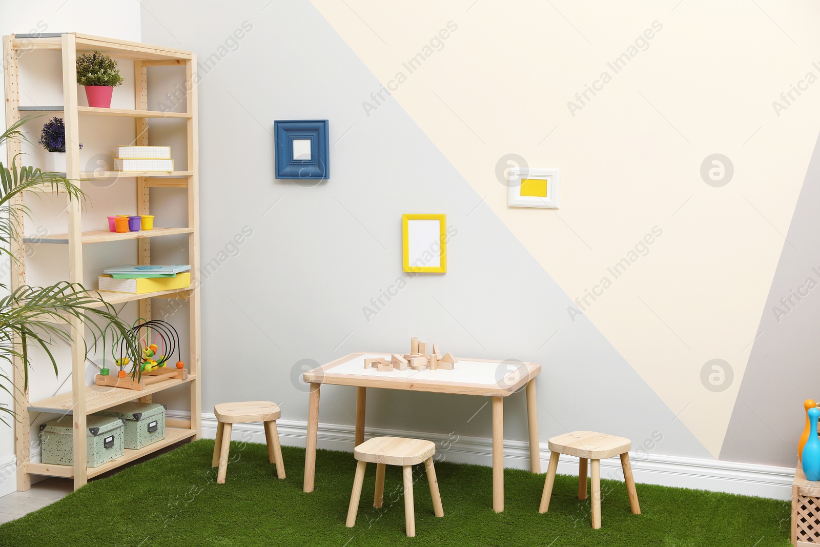 Photo of Stylish playroom interior with table, stools and green carpet