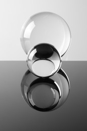 Photo of Transparent glass balls on mirror surface against light background