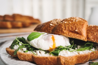 Delicious croissant with arugula and egg on plate, closeup