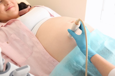 Photo of Pregnant woman undergoing ultrasound scan in clinic, closeup