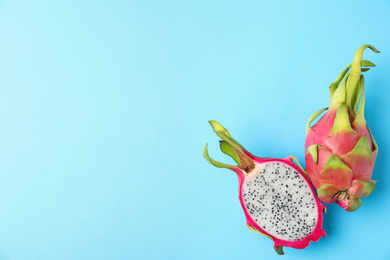 Photo of Delicious cut and whole dragon fruits (pitahaya) on light blue background, flat lay. Space for text