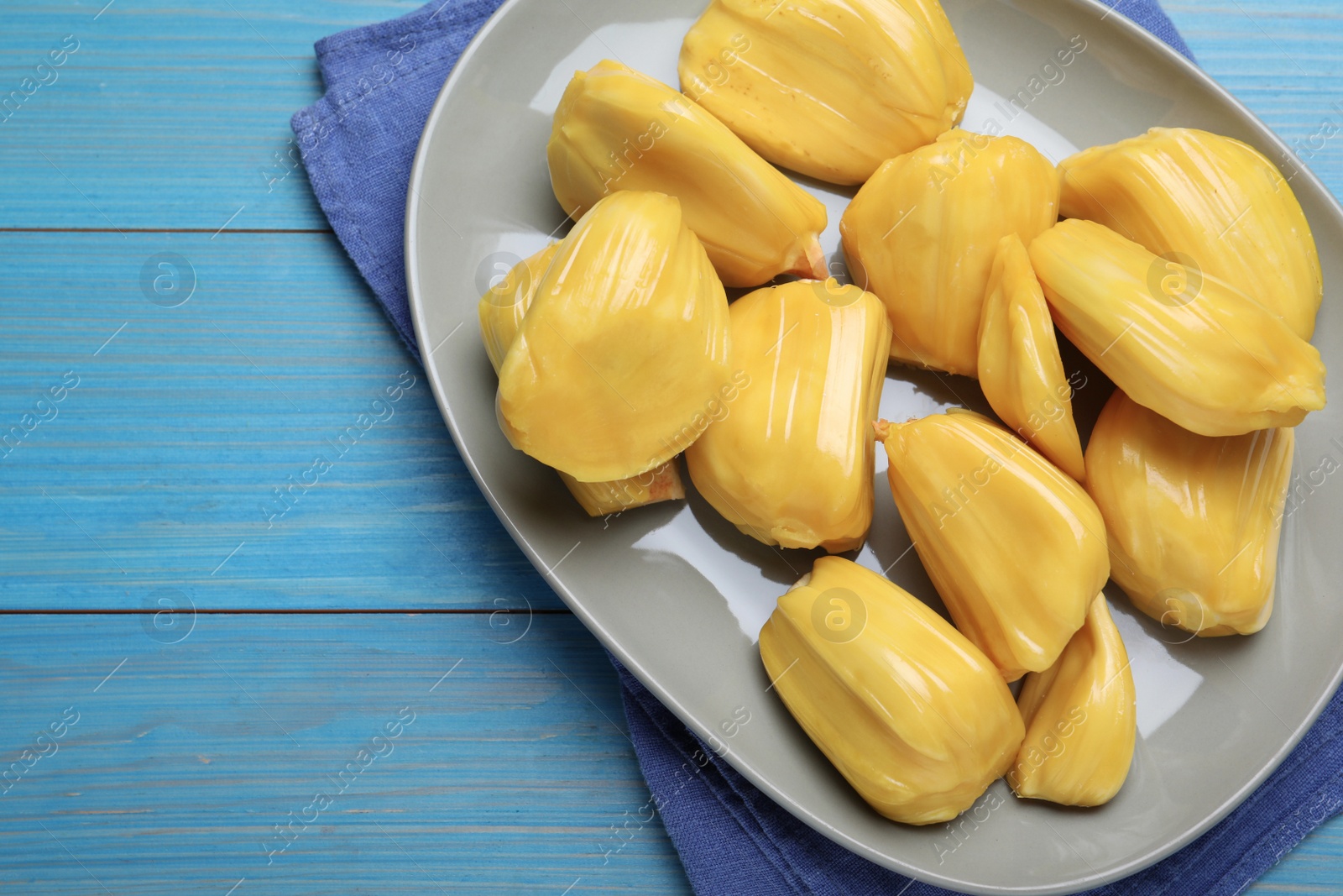 Photo of Delicious exotic jackfruit bulbs on light blue wooden table, flat lay