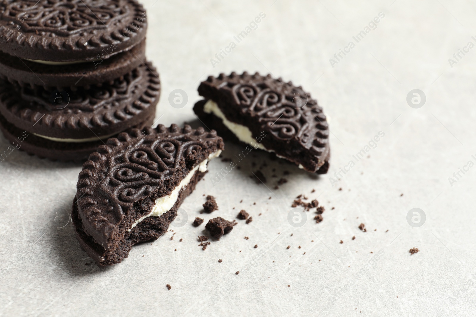 Photo of Tasty chocolate cookies with cream on grey background. Space for text