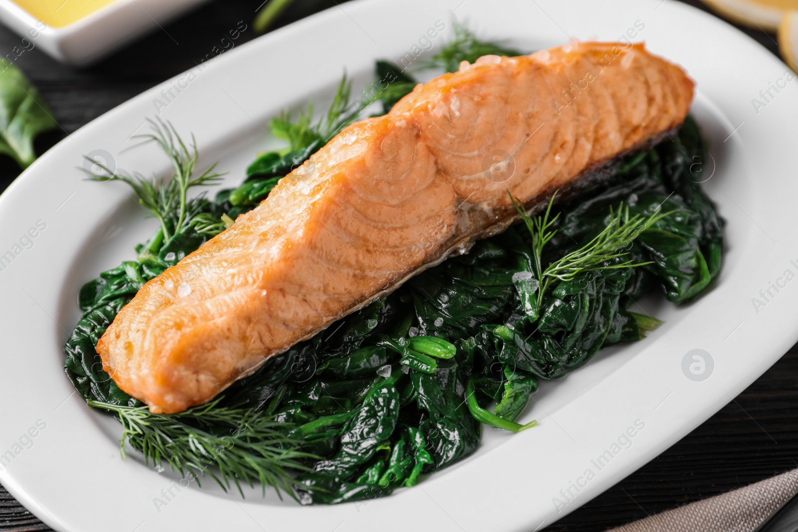 Photo of Tasty salmon with spinach on table, closeup