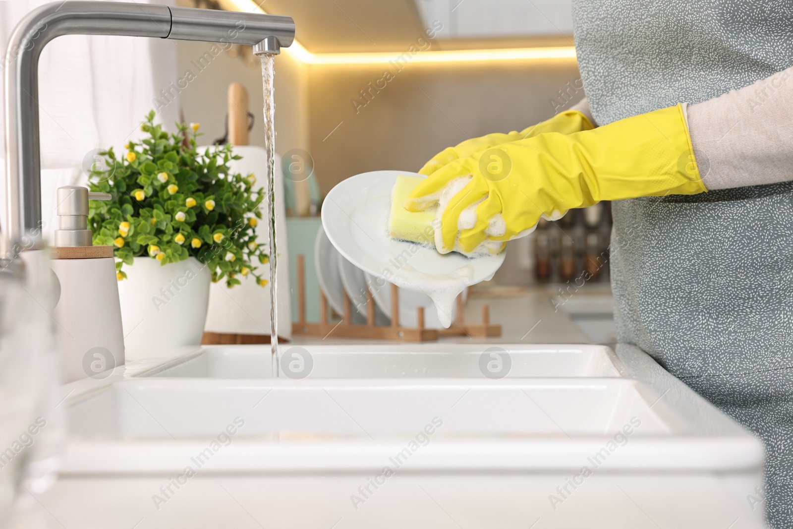 Photo of Housewife washing plate in kitchen sink, closeup
