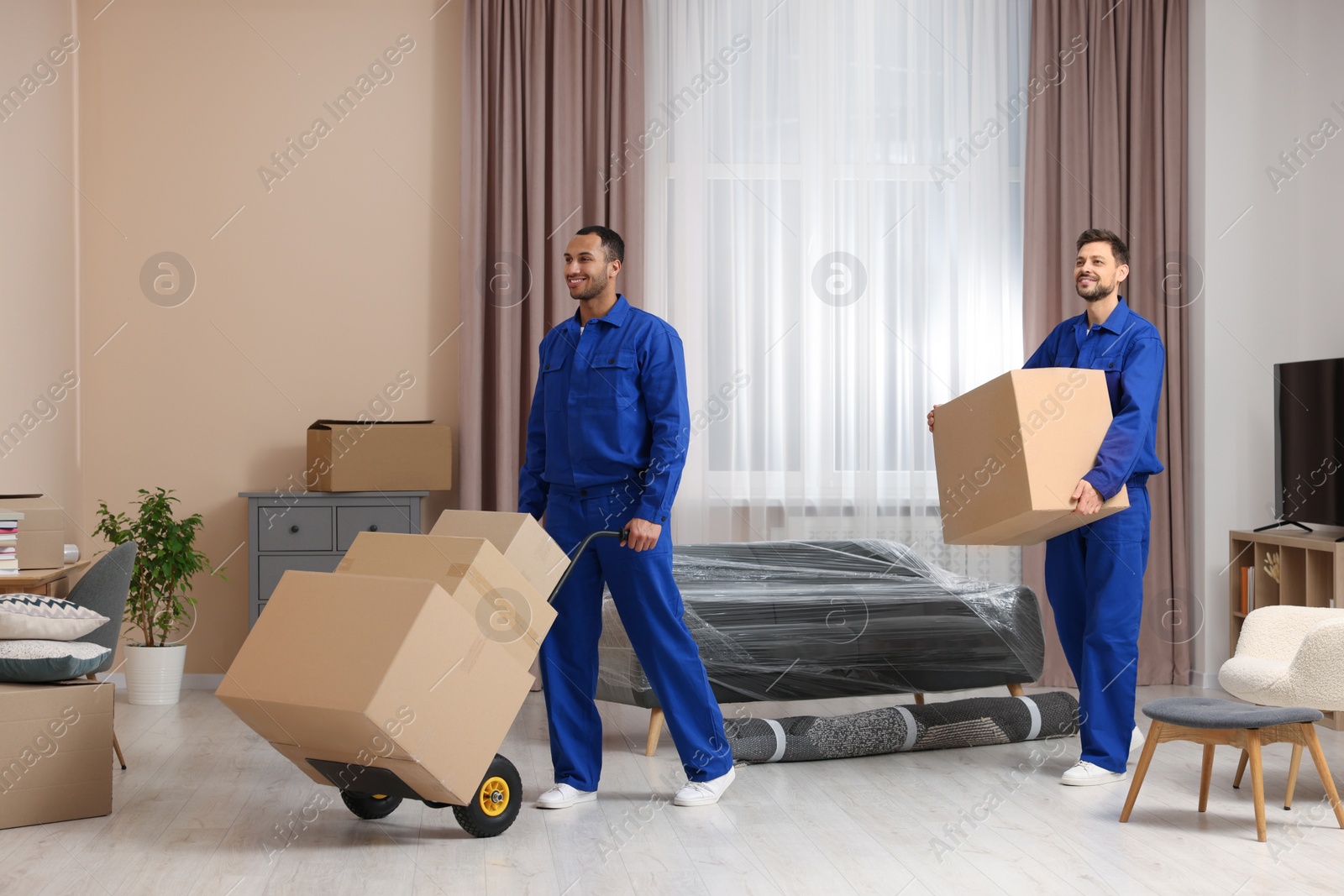 Photo of Male movers with cardboard boxes in new house