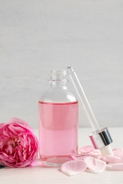Photo of Fresh flowers, bottle of rose essential oil and pipette on table, space for text