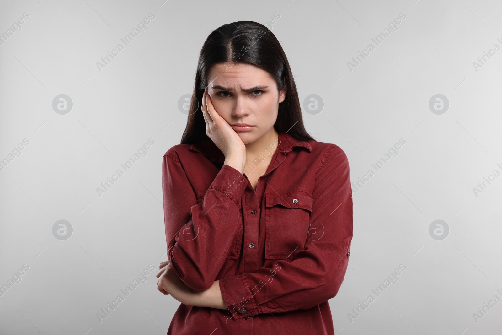 Photo of Sadness. Unhappy woman in red shirt on gray background