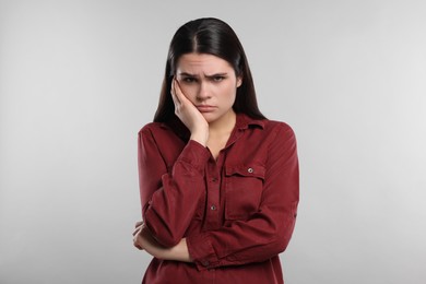 Photo of Sadness. Unhappy woman in red shirt on gray background