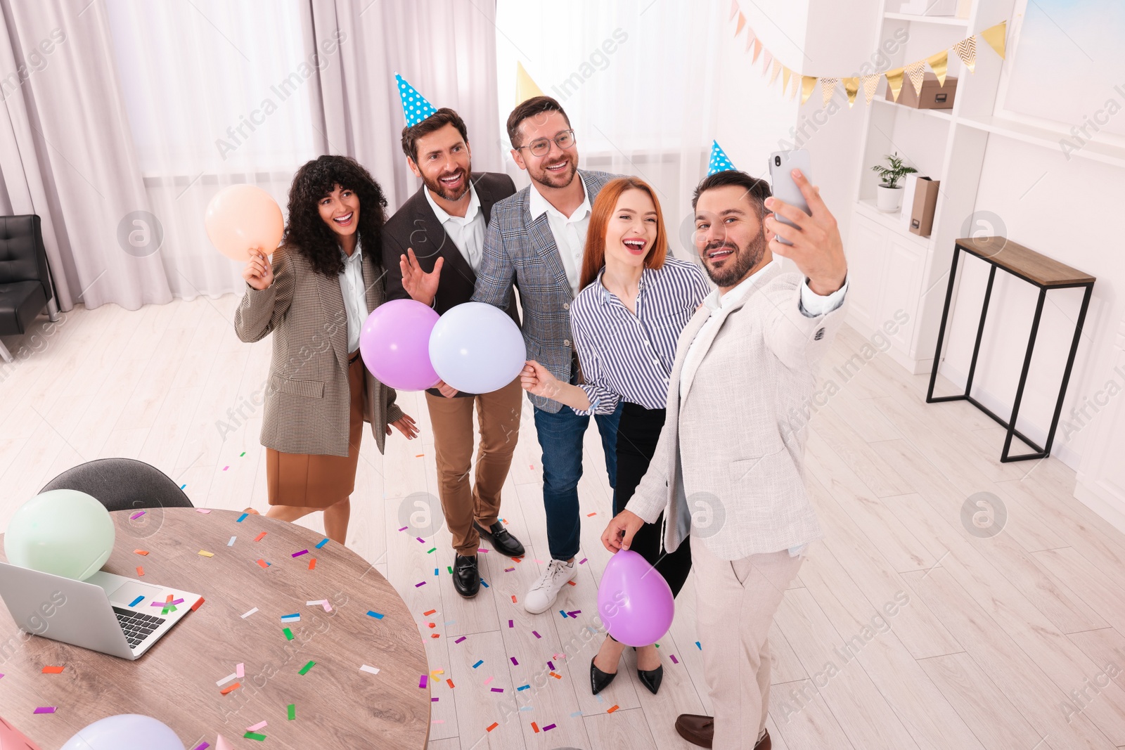 Photo of Coworkers taking selfie during office party indoors