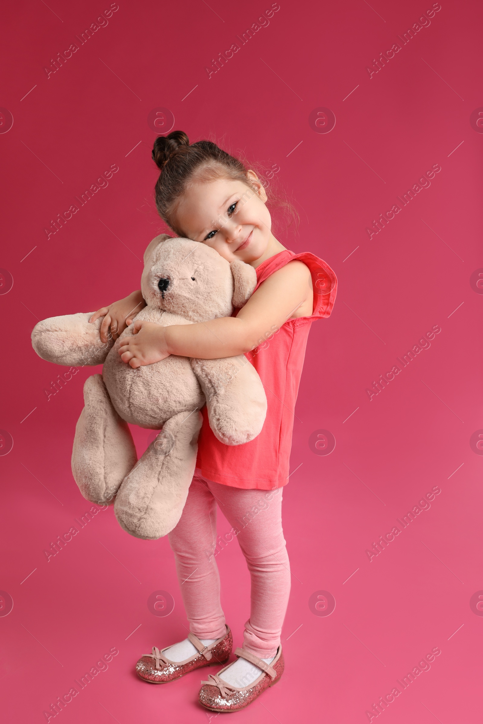 Photo of Cute little girl with teddy bear on pink background