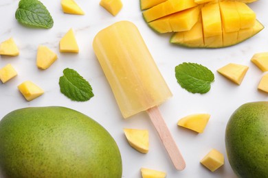 Photo of Tasty mango ice pop on white marble table, flat lay. Fruit popsicle