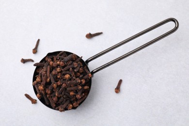Photo of Aromatic cloves in scoop on light table, top view