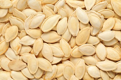 Photo of Many pumpkin seeds as background, top view