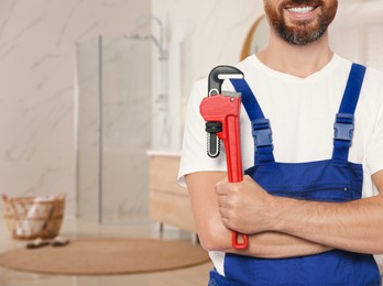 Image of Plumber with pipe wrench in bathroom, closeup. Space for text