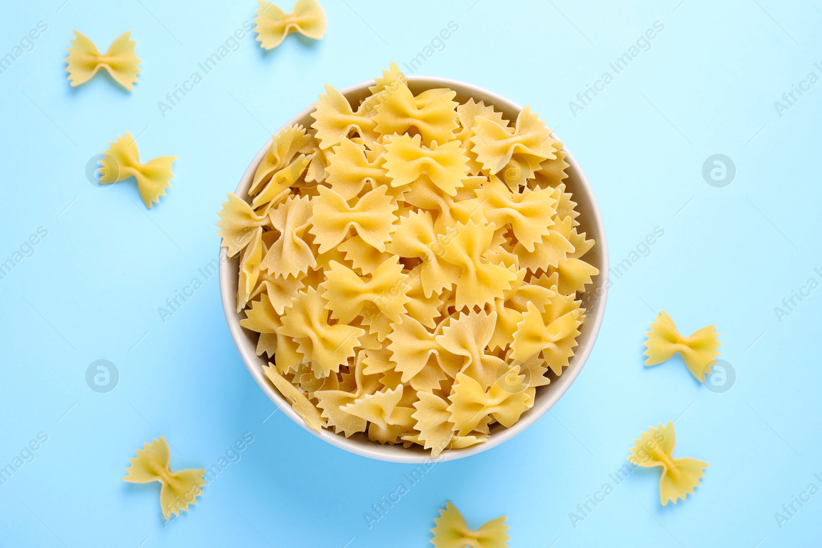 Photo of Farfalle pasta on light blue background, flat lay