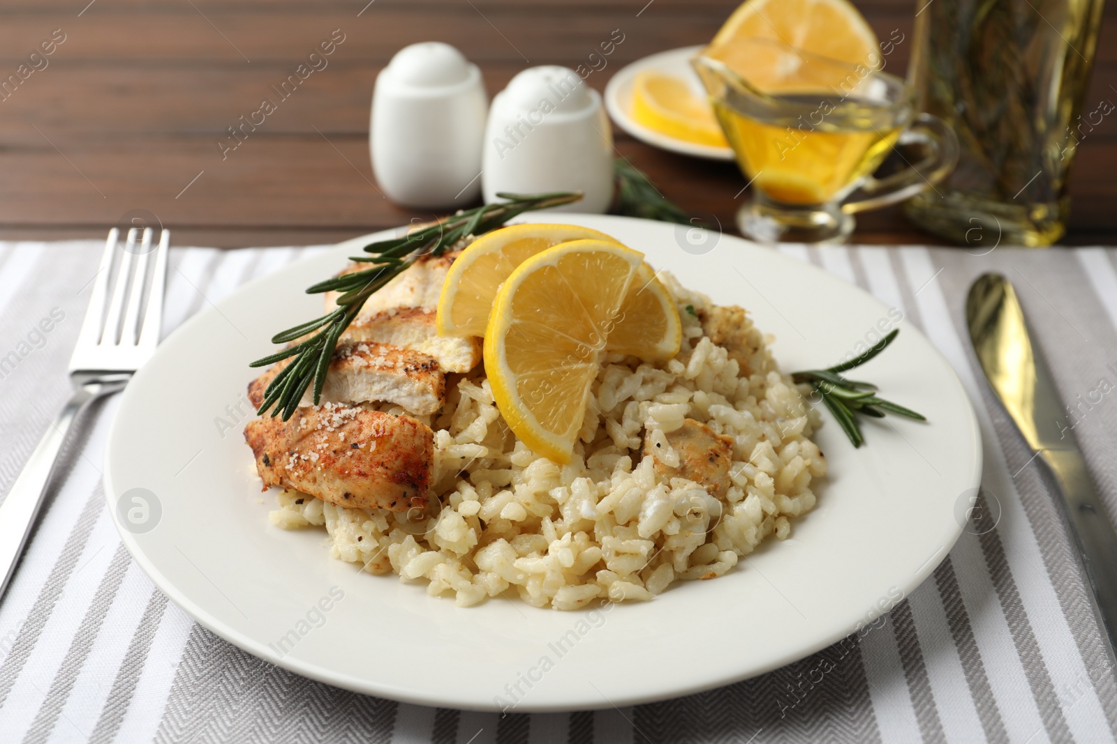 Photo of Delicious chicken risotto with lemon slices on table