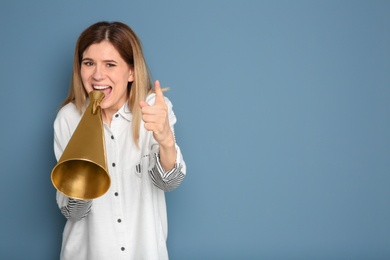 Photo of Young woman shouting into megaphone on color background