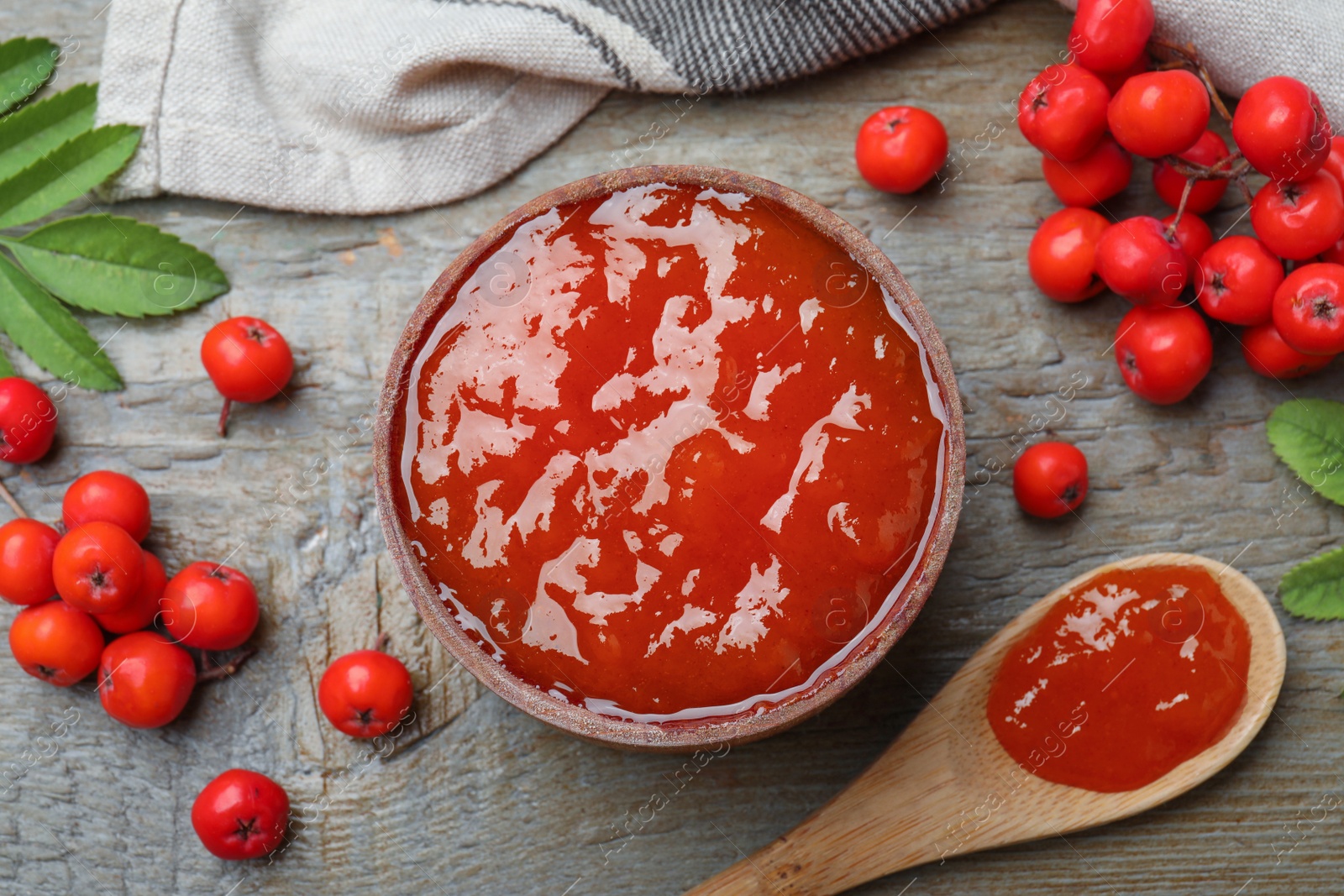 Photo of Flat lay composition with delicious rowan jam and berries on wooden table