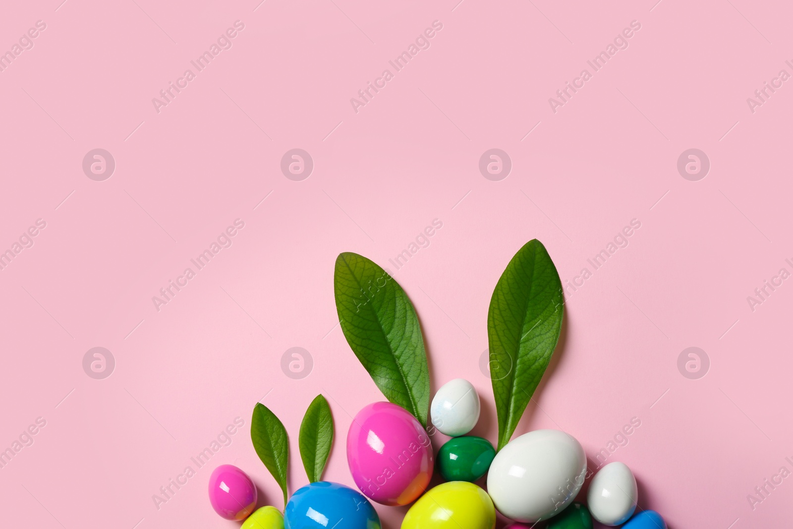 Photo of Creative flat lay composition with Easter bunny ears made of green leaves and eggs on color background, space for text