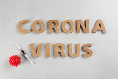 Words CORONA VIRUS and syringe on light background, flat lay