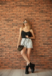 Young woman with sexy legs near brick wall